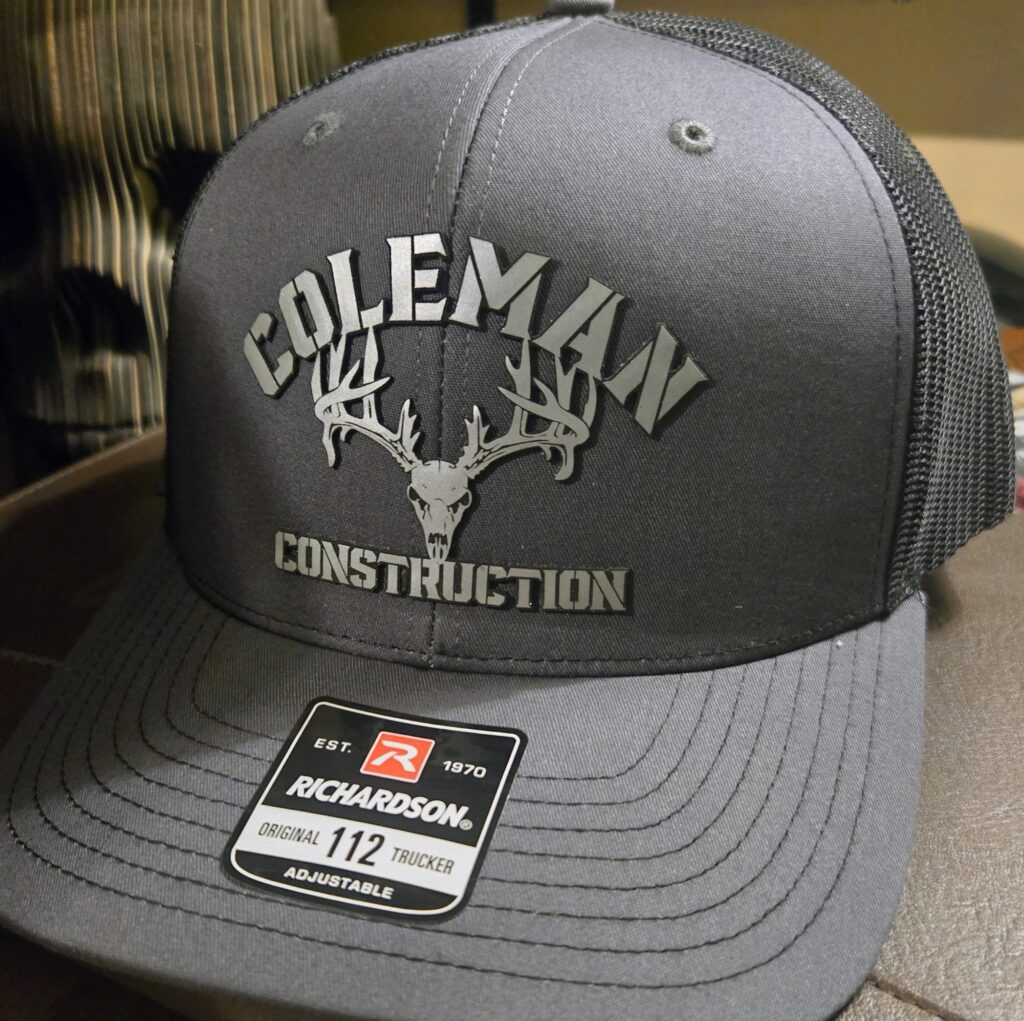 Gray Coleman Construction baseball cap with logo and deer antlers.