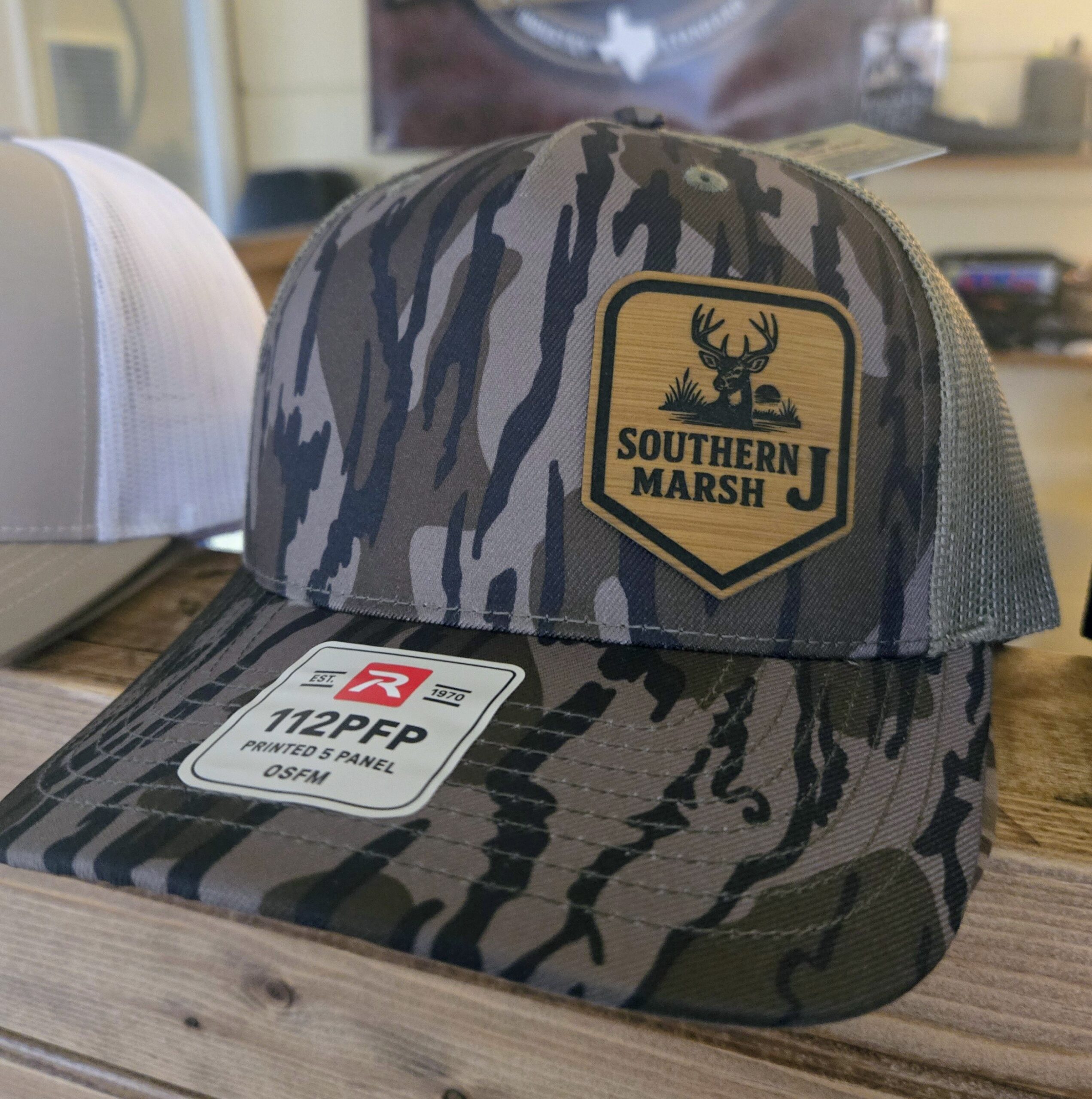 Camouflage cap with "Survival Marsh" patch and Tesco price tag.