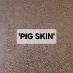 'PIG SKIN' text on a textured brown background resembling leather.